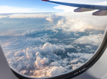 looking out airplane window into cloudy sky. tips for a better flight