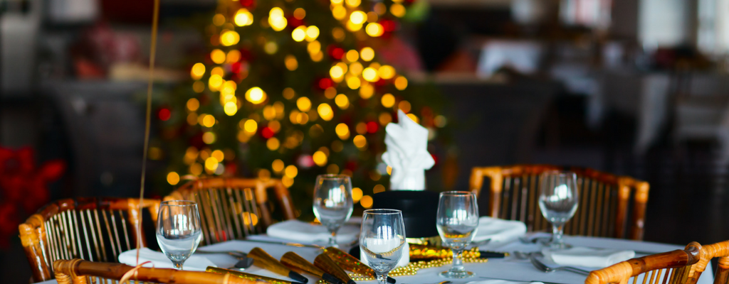dining room table with Christmas tree in background during corporate holiday party themes